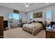 Comfortable bedroom with a ceiling fan, large windows, and a floral-patterned bedspread at 27667 W Mohawk Ln, Buckeye, AZ 85396