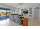 Spacious living room featuring a large gray sofa, a ceiling fan, and built-in shelving at 27667 W Mohawk Ln, Buckeye, AZ 85396