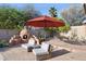 Relax in this backyard featuring a stone patio, built-in fireplace, and comfortable seating under a large umbrella at 4146 N Lomond --, Mesa, AZ 85215