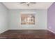 Bedroom with dark wood floors, ceiling fan, and a large window overlooking the neighborhood at 4601 N 102Nd Ave # 1178, Phoenix, AZ 85037
