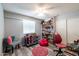 Childs' bedroom with laminate wood floors, a ceiling fan, a red dollhouse, and lots of toys on a shelf at 5751 W Muriel Dr, Glendale, AZ 85308