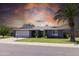 Charming single-story home with a well-manicured lawn and mature palm tree under an orange-hued sky at 5751 W Muriel Dr, Glendale, AZ 85308