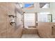 Luxurious tiled shower with dual shower heads, a built-in bench, and ample natural light from glass block window at 6135 E Campo Bello Dr, Scottsdale, AZ 85254