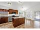 Open-concept kitchen featuring stainless appliances, wood cabinetry, and a central island, complemented by tile flooring at 6602 W Lariat Ln, Phoenix, AZ 85083