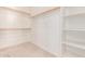 Walk-in closet featuring carpeted floor, white walls, wooden clothing rods, and built-in shelving at 7418 S 25Th Ln, Phoenix, AZ 85041