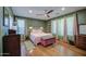 Comfortable main bedroom featuring wood floors, green walls, large windows, and a ceiling fan at 9347 E Hillview Cir, Mesa, AZ 85207