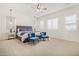 Bright main bedroom featuring neutral carpet, ceiling fan, plantation shutters, and sitting area at 12058 N Loma Linda St, Surprise, AZ 85388