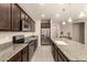 Modern kitchen featuring a center island, dark cabinets, granite countertops, and stainless steel appliances at 12109 W Tether Trl, Peoria, AZ 85383