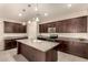 Stylish kitchen featuring a center island, dark cabinets, granite countertops, and recessed lighting at 12109 W Tether Trl, Peoria, AZ 85383