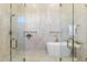 A bathroom featuring a soaking tub with glass shower, neutral tile, and gold fixtures at 12638 E Cortez Dr, Scottsdale, AZ 85259