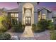 Grand front entrance with arched doorway, lush landscaping, and decorative stone pathway at 12638 E Cortez Dr, Scottsdale, AZ 85259