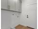 Laundry room has upper cabinets, white walls, and a light hardwood floor at 12638 E Cortez Dr, Scottsdale, AZ 85259