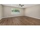 Bright living room featuring wood-look flooring, a ceiling fan, and a large window showcasing backyard view at 13805 N 31St Ave, Phoenix, AZ 85053