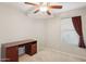 Bedroom with a ceiling fan, a desk with drawers, and a large window letting in natural light at 14822 N Tonya Cir, El Mirage, AZ 85335