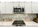Modern kitchen with stainless steel microwave and cooktop, white cabinets, and a decorative backsplash at 1809 E Gwen St, Phoenix, AZ 85042