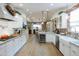 Open concept kitchen with white cabinetry, stainless steel appliances, brick accent wall, and wood-look flooring at 2111 W Mulberry Dr, Phoenix, AZ 85015