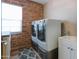 Well-lit laundry room featuring brick wall, modern washer and dryer, and built in sink and cabinet at 2111 W Mulberry Dr, Phoenix, AZ 85015