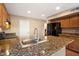 Spacious kitchen boasts granite countertops, wood cabinets, and stainless steel sink and faucet at 21665 N 47Th Pl, Phoenix, AZ 85050
