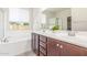 Bathroom featuring double sinks, a soaking tub, walk-in shower, and a large mirror at 25945 W Runion Dr, Buckeye, AZ 85396