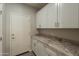 Well-lit laundry room boasts ample cabinet space and granite countertops at 2680 E Daniel Dr, Gilbert, AZ 85298
