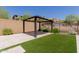 Well-maintained backyard with a cozy gazebo on a stone patio, surrounded by artificial turf and greenery at 34009 N 29Th Dr, Phoenix, AZ 85085