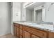 Bathroom featuring double sinks with granite counters, wood cabinets, large mirror, and light fixtures at 3811 W Loma Ln, Phoenix, AZ 85051