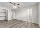 Spacious bedroom with ceiling fan, closet, wood-look flooring, and a glimpse into the bathroom at 3811 W Loma Ln, Phoenix, AZ 85051