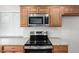 Close up of stainless steel microwave and electric stove over granite countertops and wooden cabinets at 3811 W Loma Ln, Phoenix, AZ 85051