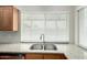 Stainless steel dual sink in front of bright window with granite countertops and wood cabinets at 3811 W Loma Ln, Phoenix, AZ 85051