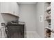 Functional laundry room with front load washer, white cabinets, and storage shelves for organization at 4091 W Suncup Dr, San Tan Valley, AZ 85144