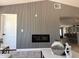 Modern living room with linear fireplace, wood accent wall and open floor plan to kitchen at 4416 E Capistrano Ave, Phoenix, AZ 85044