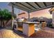 Outdoor kitchen under a pergola, with a built-in grill, bar and nice seating at 5113 W Molly Ln, Phoenix, AZ 85083