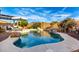 Luxurious backyard pool with natural rock features, mature trees, patio seating, and outdoor dining area at 5113 W Molly Ln, Phoenix, AZ 85083
