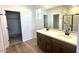 Modern bathroom with dual sinks, dark wood cabinets, and glass shower enclosure at 5657 S 253Rd Ave, Buckeye, AZ 85326