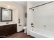 Bright bathroom featuring a soaking tub and shower combo, large mirror, and dark cabinets at 6502 W Wahalla Ln, Glendale, AZ 85308