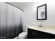 Bathroom featuring shower with dark-to-light gray shower curtain, sink with black vanity and toilet at 8202 W Turney Ave, Phoenix, AZ 85033