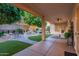 Covered patio overlooking backyard oasis with a fountain and mature trees at 9326 E Princess Dr, Mesa, AZ 85207