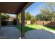 Relaxing covered patio overlooks green lawn, blooming bushes, and block fence at 9571 E Nittany Dr, Scottsdale, AZ 85255
