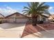 Charming single-story home featuring a three-car garage, palm tree, and desert landscaping at 11065 W Runion Dr, Peoria, AZ 85373