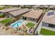 Aerial view of a private backyard featuring a pool with a spa, patio dining, fire pit, and manicured artificial turf at 11951 W Wier Ave, Avondale, AZ 85323