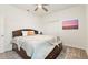 Bedroom with a large bed, neutral carpet, modern ceiling fan, and muted wall art at 11951 W Wier Ave, Avondale, AZ 85323