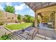 Well-manicured backyard with grassy area, desert plants, pavers, and a covered patio at 12932 W Cassia Trl, Peoria, AZ 85383