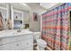 Well-lit bathroom features a white vanity, toilet, and a colorful patterned shower curtain at 12932 W Cassia Trl, Peoria, AZ 85383