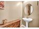 Stylish powder room with unique rustic accents including wood cabinet and white pedestal sink at 12932 W Cassia Trl, Peoria, AZ 85383