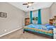 Cozy bedroom featuring a ceiling fan, window with blinds, and a comfortable-looking bed with blue accents at 12932 W Cassia Trl, Peoria, AZ 85383