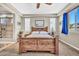 Bright main bedroom with a large window, plantation shutters, and a wooden bed frame at 12932 W Cassia Trl, Peoria, AZ 85383