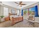 Cozy main bedroom featuring natural light, a ceiling fan, and a chair with an ottoman at 12932 W Cassia Trl, Peoria, AZ 85383