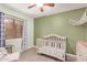 Charming Bedroom with light green walls, a crib, wood-look tile floors, and plenty of light at 13216 W Desert Ln, Surprise, AZ 85374