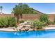 Relaxing pool with a rock waterfall feature and mature landscaping at 13216 W Desert Ln, Surprise, AZ 85374