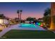 Lush backyard with a sparkling pool, decorative lighting, palm trees, lounge chairs and beautiful landscaping at 14012 N 57Th Pl, Scottsdale, AZ 85254